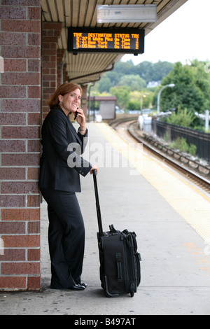 Commuting businesswoman keeps busy while awaiting the arrival of her train Stock Photo