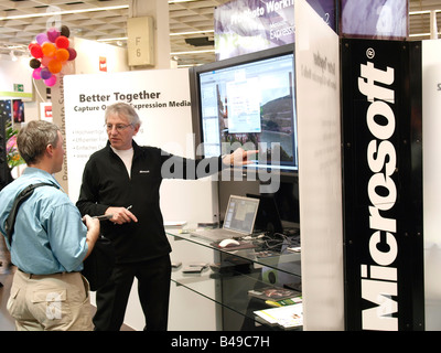 Microsoft employee explaining something to a customer on a big flatscreen monitor Photokina Cologne Germany Better Together Stock Photo