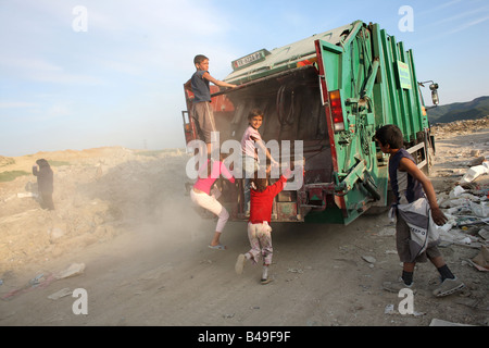 Children riding a dumpster in Sharre,  a slum next to a rubbish dump on the outskirts of Tirana, Albania Stock Photo