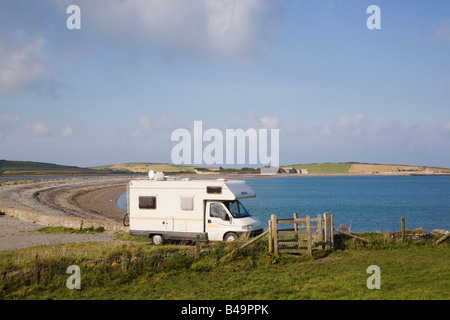 Motorhome parked at seaside by beach in rural beauty spot on coast. Cemlyn Bay Anglesey Wales UK Britain Stock Photo