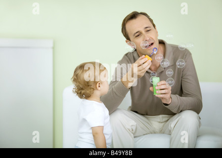 Father and toddler blowing bubbles together Stock Photo