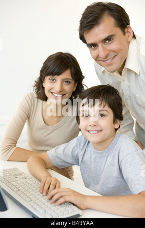 Boy with parents, using keyboard, all smiling at camera Stock Photo