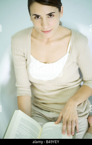 Woman holding open book, smiling at camera, high angle view Stock Photo