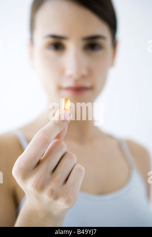 Woman holding vitamin capsule, focus on foreground Stock Photo