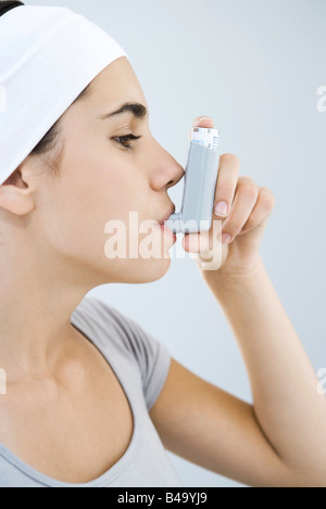 Teen girl using inhaler, side view Stock Photo