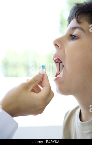 Child accepting pill with open mouth, cropped view Stock Photo