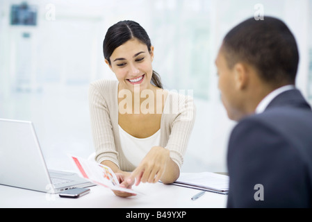 Professional woman reviewing brochure with customer Stock Photo