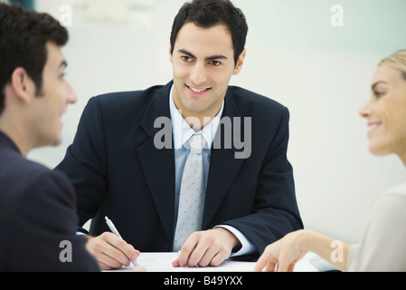 Business associates having discussion, smiling at each other, man taking notes Stock Photo