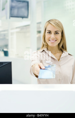 Travel agent holding out ticket, smiling at camera, personal perspective Stock Photo