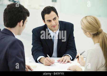 Meeting between professional and clients, woman preparing to sign document Stock Photo