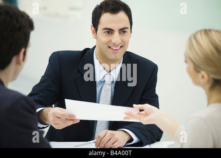 Meeting between professional and clients, man passing document to woman Stock Photo