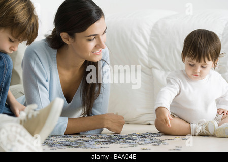 Mother and two children putting together jigsaw puzzle Stock Photo