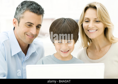 Family using laptop computer together, smiling Stock Photo