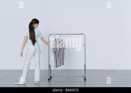 Woman looking at tee-shirts hanging on rack, rear view Stock Photo