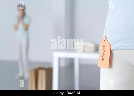 Close-up of sale tag on shirt, woman standing in background Stock Photo