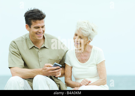Senior woman with adult son looking at his wireless device Stock Photo