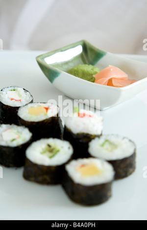 Rows of maki sushi, dish of pickled ginger and wasabi Stock Photo