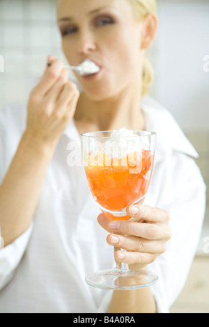 Woman eating jellied fruit dessert with whipped cream Stock Photo