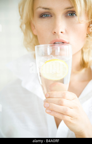 Woman holding up glass of water, looking at camera Stock Photo