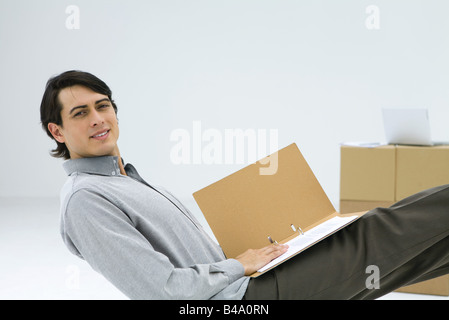 Man sitting at cardboard box desk, using laptop computer Stock Photo