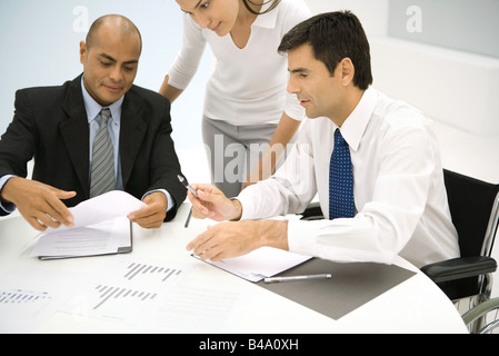 Associates discussing documents, one man in wheelchair Stock Photo