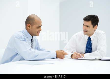 Two businessmen sitting at table, discussing document Stock Photo