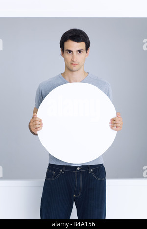 Man holding blank circular sign, looking at camera Stock Photo