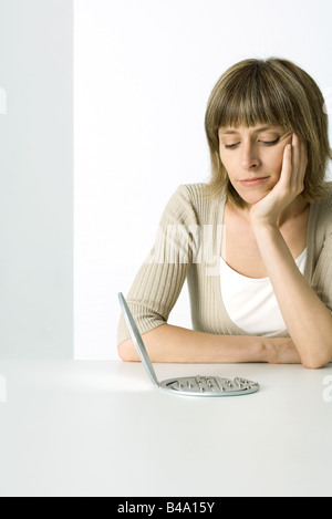 Woman contemplating electronic game, hand under chin Stock Photo