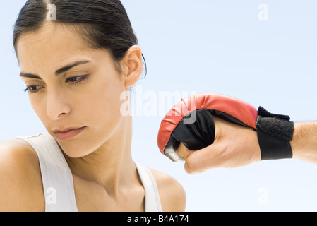 Woman turning head away from hand in boxing glove, close-up Stock Photo