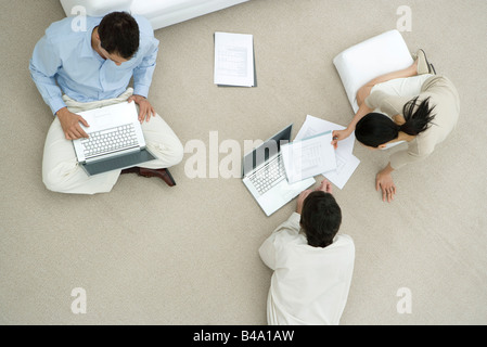 Professionals working together on floor, two discussing document, overhead view Stock Photo