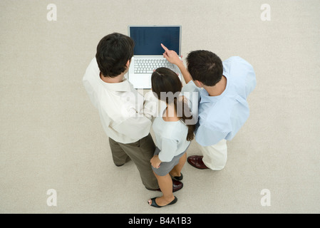 Three professionals standing, looking at laptop computer together, high angle view Stock Photo