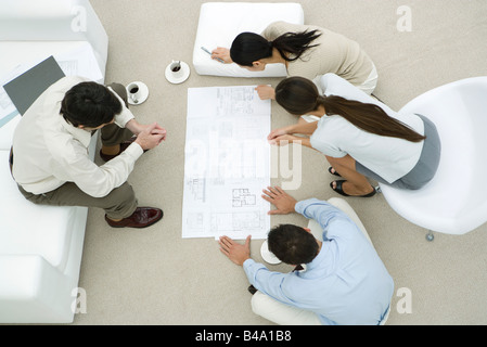 Team of professionals looking at blueprint together, overhead view Stock Photo