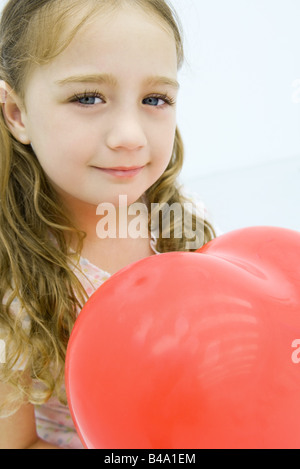 Little girl holding heart shaped balloon, close-up
