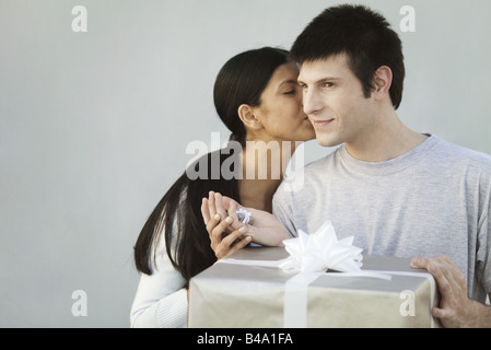 Couple exchanging gifts, woman kissing man on cheek Stock Photo