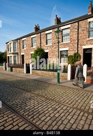 Woman in period costume walking past the recreation of a row of Edwardian terraced housing, Beamish, County Durham, England Stock Photo