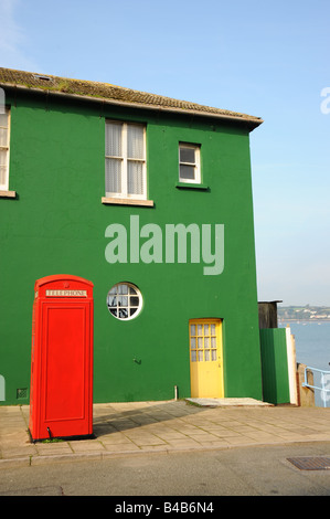 Green House with red telephone box and yellow door by the sea Stock Photo