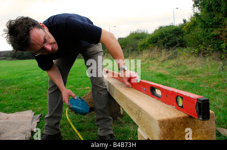 Man using spirit level during construction of a bench to enliven a public space Hounslow, Middlesex, UK. Stock Photo