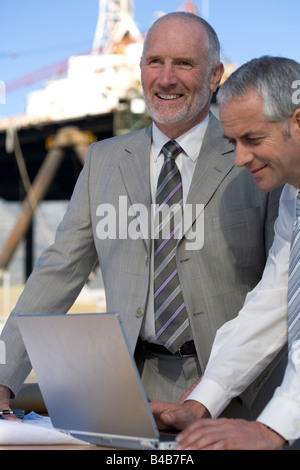 Two engineers studying plans on their laptop Stock Photo