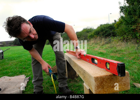 Man using spirit level during construction of a bench to enliven a public space Hounslow, Middlesex UK Stock Photo