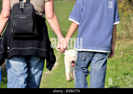 Mother and child walking and holding hands on a dog walk Stock Photo