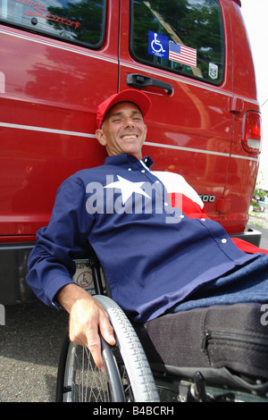 Casual Portrait of Man in a Wheelchair  He is Wearing a Red White and Blue Shirt with a Star on it and is Leaning Against a Van Stock Photo