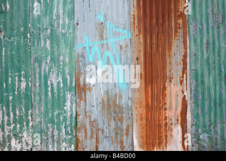 Rusting corrugated iron sheeting and sprayed graffiti on wasteland in Canning Town, Newham, East London Stock Photo