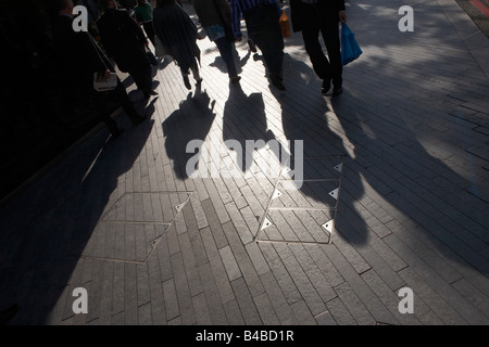 Long commuters' shadows seen across pavement during transport chaos during tube strike near London Bridge Station. Stock Photo