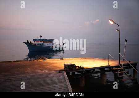 Fishermen set off from a jetty at dawn to fish for yellowfin tuna aboard a traditional dhoni boat on the Indian Ocean Stock Photo