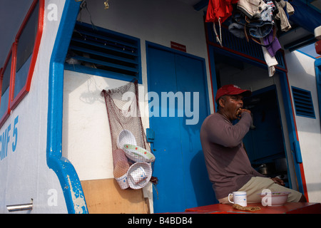 A Maldivian crewman eats after a day's yellowfin tuna fishing aboard a traditional dhoni fishing boat on the Indian Ocean Stock Photo