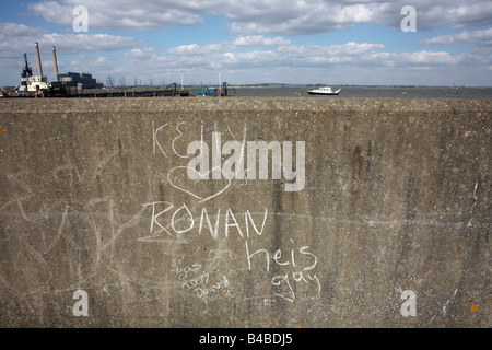 Teenage love graffiti has been written in chalk on the Thames flood wall located on the Saxon Shore Way at Gravesend Stock Photo