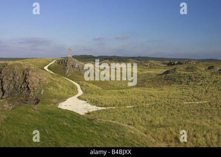 Footpath leading to stone cross on top of mound at Llanddwyn Island, Anglesey in November. Stock Photo