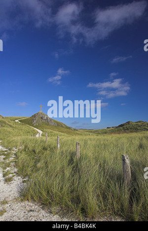 Footpath leading to stone cross on top of mound at Llanddwyn Island, Anglesey in November. Stock Photo