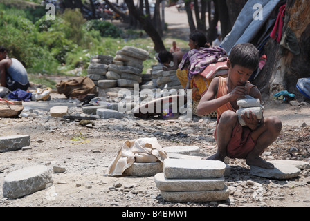 Small nepalese boy works hard with stones in suburbs of Kathmandu Stock Photo