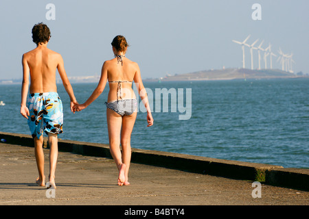 Couple young teenage man woman lover hand holding walking swimming suit on levee dyke Hoek van Holland Netherlands sunny summer Stock Photo